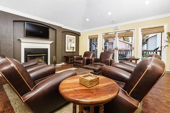 A living room with leather chairs and a table and a fireplace